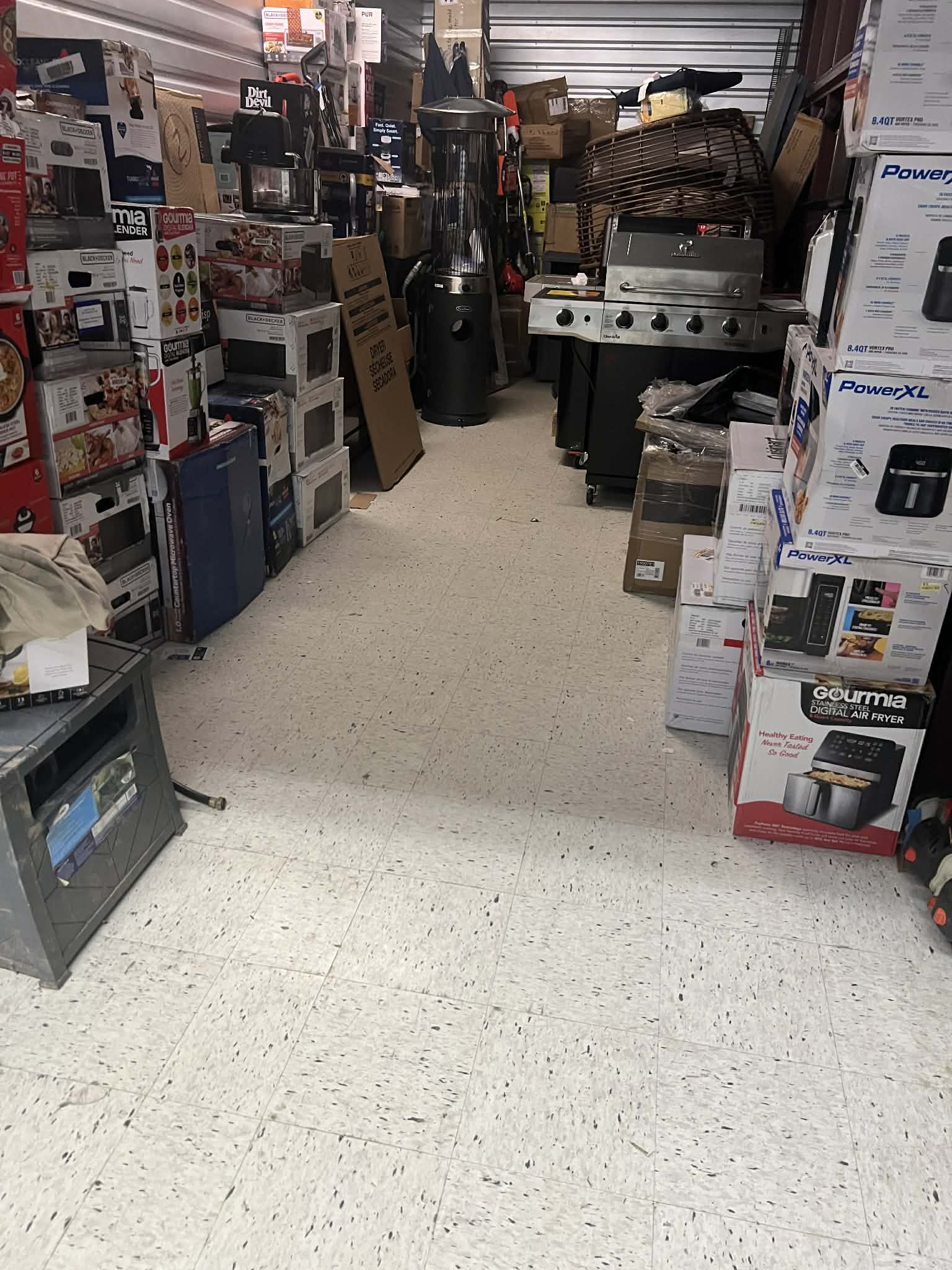 Main warehouse aisle lined with grills, heaters, microwaves, and stacked air fryers