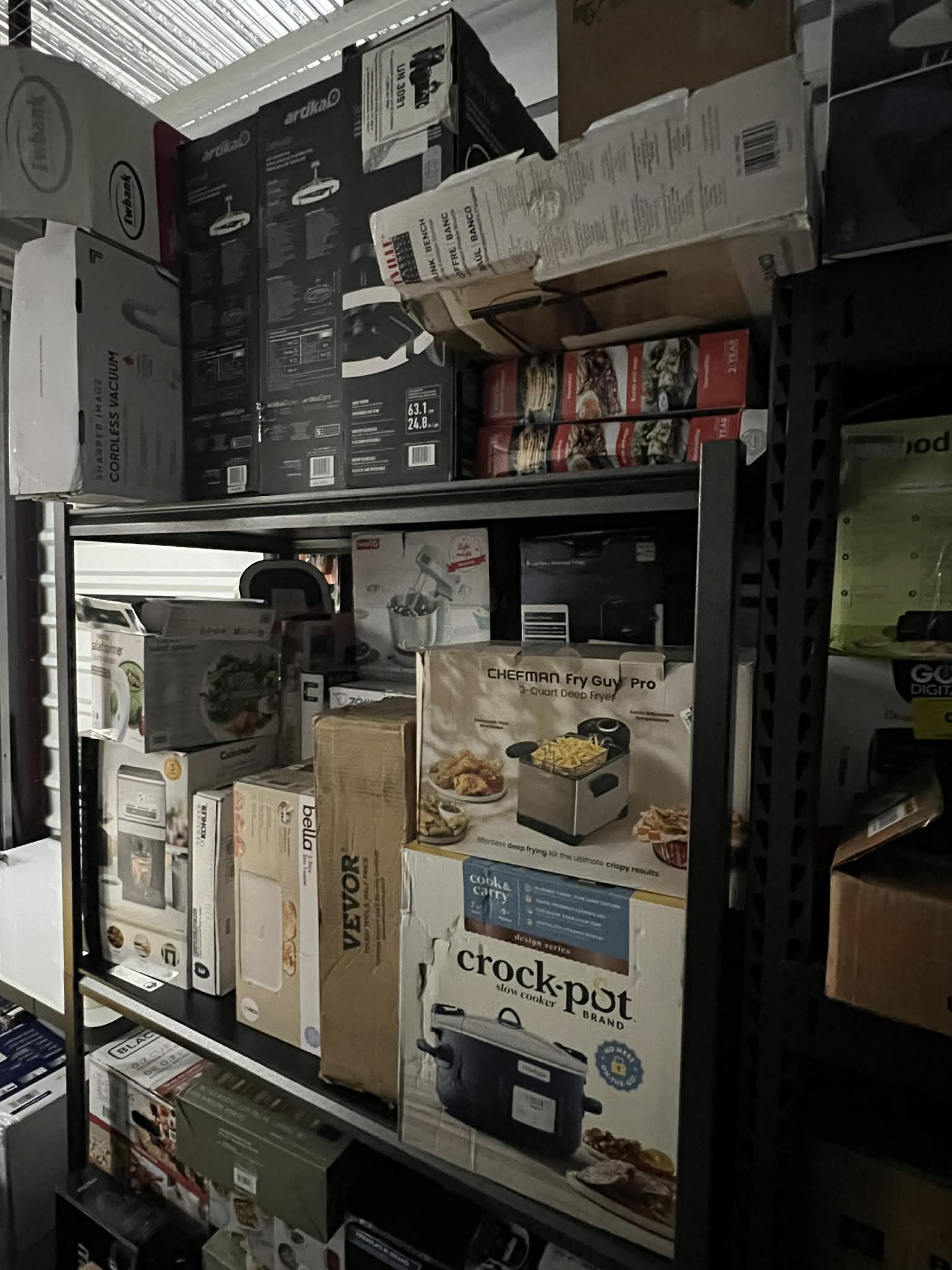 Kitchen appliances like slow cookers, fryers, and mixers organized on warehouse shelving